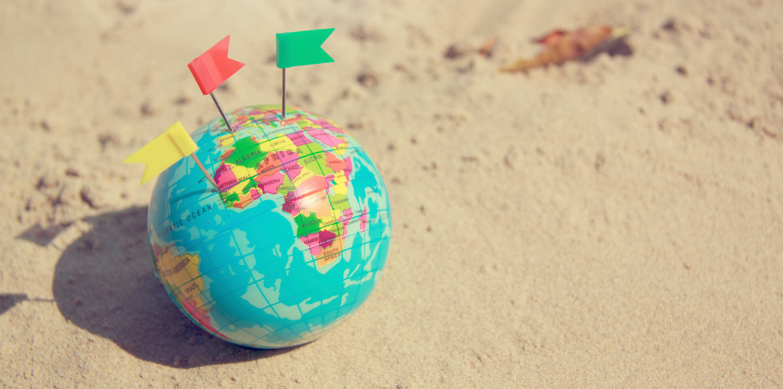 Travel Summer Concept with Earth Map Ball on Sand